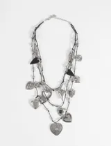 Collar de tres hileras de cordón negro con múltiples dijes metálicos en forma de corazón de diversos estilos y tamaños, intercalados con cuentas metálicas plateadas.