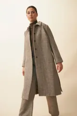 Tapado con cuello solapa y corte recto, color gris. Cierre frontal con botones ocultos, tajos laterales y bolsillos escondidos en corte lateral. Con forro. Tela 100% lana fina sin teñir, diseñada exclusivamente por Don Baez. Hecha 100% en Uruguay.