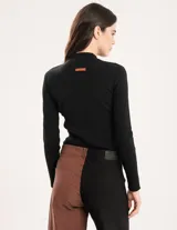 Polera negra de tejido de punto acanalado, con cuello alto y mangas largas.