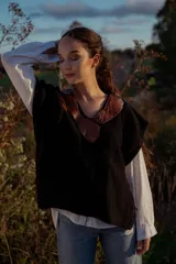 Chaleco tejido negro con cuello en V y aplique de cuero marrón.