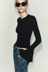 Camiseta de cuello redondo y manga larga, confeccionada en tejido rib con mezcla de lyocell. Presenta un diseño ajustado con terminación de volantes en los puños y bajo recto.