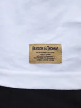 Remera blanca de algodón con estampado minimalista de la marca NOSN38 & THOMAS y una línea vertical negra.