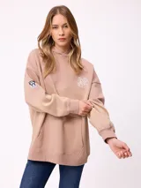 Canguro oversize color negro con efecto degradado, capucha, bolsillo frontal tipo canguro y puños elásticos. Presenta un parche con logo en la manga.