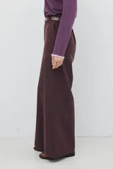 Pantalon de corte sastrero y pierna ancha, confeccionado en tela melange. Presenta cintura con trabillas, cierre frontal con botón y bolsillos laterales.