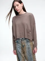 Sweater de tejido de punto color beige, con cuello redondo, hombros caídos y costura central vertical en el frente. Presenta un diseño de corte relajado, con largo asimétrico y aberturas laterales en el ruedo.