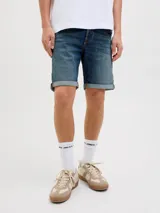 Bermuda de jean azul con efecto gastado y dobladillo revuelto en las piernas, de corte clásico.