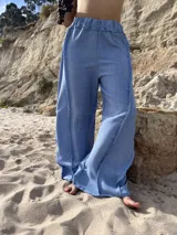 Pantalón ancho de tiro alto, color celeste claro, con costuras visibles en contraste que recorren verticalmente las piernas.