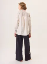 Camisa de manga larga con diseño combinado. Presenta mangas y parte superior delantera y trasera en color negro liso, mientras que el panel central de la espalda destaca por un estampado animal print de leopardo. Cuenta con cuello clásico, cierre frontal de botones y puños abotonados.