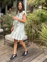 Vestido corto de lino metalizado color gris claro, con volados en los hombros y en el ruedo.