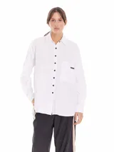 Camisa oversized de algodón color gris claro, con cuello clásico, botones negros y bolsillo frontal con etiqueta de marca.