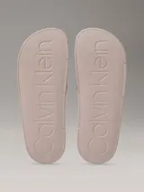 Ojotas de diseño anatómico con tira ancha superior estampada con el monograma de la marca. Presentan plantilla contorneada para mayor confort y suela de material sintético.