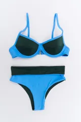 Bikini de dos piezas en combinación de colores negro y mostaza. El corpiño es de estilo triangular con base y breteles finos, mientras que la bombacha es de corte clásico con cintura alta en color negro.