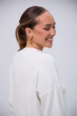 Sweater blanco de punto con cuello redondo, mangas largas y corte holgado con aberturas laterales.