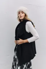 Chaleco negro con interior y bordes de piel sintética, diseño abierto sin cierre.