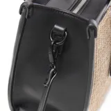 Cartera mediana tipo tote con cuerpo tejido en rafia de color beige y detalles en cuero sintético negro, incluyendo asas de mano, ribetes y correas frontales decorativas con hebillas. Cuenta con una correa larga ajustable y desmontable, y placa metálica con el logo de la marca en el frente.