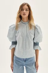 Blusa de algodón a cuadros en tonos celestes y beige, con mangas abullonadas, cuello alto y detalles de punto smock en cuello y puños.