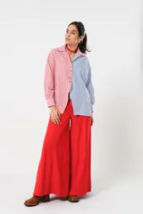 Camisa a rayas rojas y blancas en un lado y azules y blancas en el otro, con corte en A y abertura central con botonadura doble.