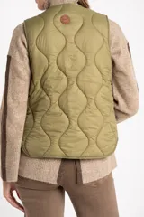 Chaleco capitoneado color verde oliva, con cierre frontal de botones, cuello redondo y diseño acolchado con costuras onduladas.