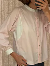 Camisa de algodón color rosado, con cuello mao y detalles en color blanco en el cuello, puños y paneles laterales. Presenta cierre frontal con botones y mangas largas.