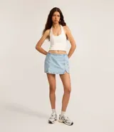 Short pollera de jeans celeste claro, tiro bajo, con ruedo deshilachado y un tajo lateral con detalle de encaje blanco en el borde.