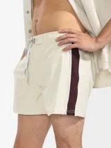 Short de baño para hombre color azul marino, con calce relajado y una tira lateral blanca estilo tuxedo. Presenta cintura elástica con cordón regulable, bolsillos laterales y trasero con cierre.