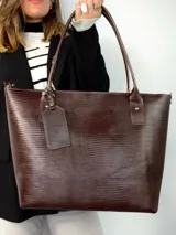Cartera tipo tote de cuero genuino color marrón oscuro con textura de reptil. Cuenta con doble asa de hombro, cierre superior y un dije colgante de cuero a tono.