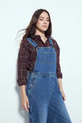 Enterito de denim negro con calce relajado y silueta amplia, inspirado en la estética workwear. Presenta tiradores regulables, pechera con bolsillo frontal y bolsillos laterales funcionales.