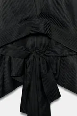 Camisa negra de cuello redondo y manga larga ancha con silueta fluida, con cierre frontal de botones y aberturas laterales en el bajo.