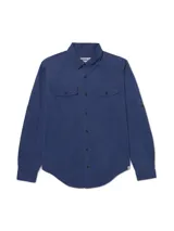 Camisa de manga larga Caterpillar de color azul, confeccionada en mezcla de tencel y algodón. Cuenta con cuello clásico, cierre frontal de botones, dos bolsillos en el pecho con solapa y botones, y diseño con mangas convertibles tipo roll-tab.