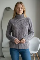 Sweater de cuello alto tipo polera, confeccionado en tejido de chenille con textura suave y diseño de trenzas verticales en el frente. Posee mangas largas con puños acanalados y ruedo también acanalado.