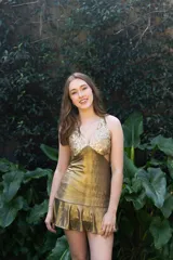 Vestido corto negro con estampado de plumas doradas, escote en V, breteles finos cruzados en la espalda, cut-outs laterales y volado en el ruedo.