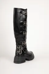 Bota de caña alta color negro, con suela track y múltiples hebillas metálicas.