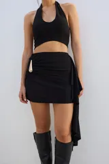 Minifalda negra con drapeado lateral y aplique metálico dorado.