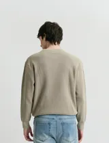 Sweater de punto con textura en color verde oscuro, de cuello redondo y manga larga.