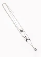 Conjunto de cuatro collares plateados de diferentes largos. El primero es una cadena simple, el segundo tiene un dije de concha, el tercero tiene cuentas y un dije de media luna, y el cuarto tiene un dije de caracol.