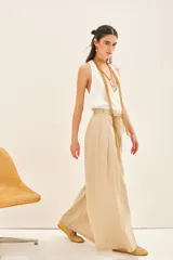 Pantalón de corte recto y amplio, confeccionado en algodón. Presenta pinzas en el delantero, bolsillos laterales y un lazo ajustable en la cintura, con elástico en la parte trasera para un mejor calce.