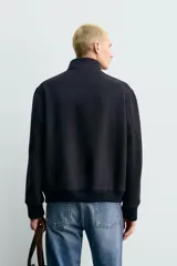 Cazadora de corte regular fit confeccionada en tejido de mezcla de lana y cashmere. Presenta cuello subido con cierre de botones, cierre frontal con cremallera de doble dirección, bolsillos laterales de vivo y acabados en rib de punto en puños y cintura.
