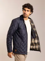Campera acolchada azul marino con cuello de pana, cierre frontal con cremallera y bolsillos con solapa en el pecho.
