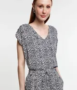 Blusa de crepé estampada en blanco y negro, con escote en V, mangas cortas y detalle de botones en los hombros.