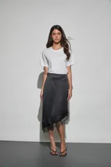 Pollera midi de satén color negro, con corte asimétrico y detalle de encaje en el ruedo.