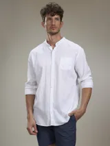 Camisa de lino blanca de manga larga con cuello mao, cierre frontal con botones y un bolsillo aplicado en el pecho.