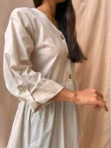 Camisa color crudo con cuello en V, abotonada al frente, con mangas 3/4 con botón para sujetar y corte evasé.