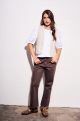 Chaleco sin mangas, color beige claro, con bordados florales en relieve y ribetes a contraste.