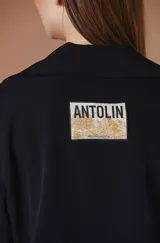 Saco negro de corte corto y silueta relajada, con solapas amplias y botones frontales.
