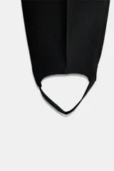 Pantalón negro de tiro alto con detalle de nervio en el delantero y bajo acabado en fuseau. Cierre frontal con cremallera, botón y ganchos metálicos.