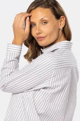 Camisa de manga larga con rayas verticales grises y blancas, corte holgado y bolsillo en el pecho.