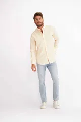 Camisa de hombre color crema, de corte clásico, con cuello abotonado y mangas largas.