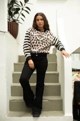 Saco de punto con diseño combinado de estampado animal print en el cuerpo y rayas horizontales en las mangas. Presenta cuello redondo, cierre frontal con botones y terminaciones en tejido acanalado negro.