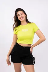 Remera corta color verde lima, de corte ajustado y mangas cortas. Presenta estampado frontal con la leyenda "Manhattan 1990 New York".