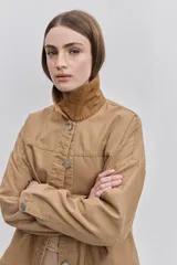 Campera de gabardina tostada, con cuello camisero de pana marrón, cierre frontal de botones metálicos y bolsillos delanteros aplicados con solapa.
